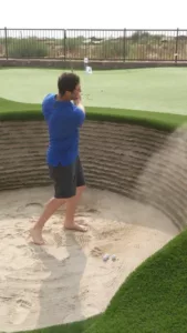 Jon Rahm hitting out of his stacked sod bunker